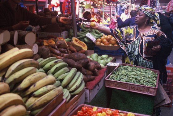 Woman in traditional African dress shopping for fruit in Brixton Market